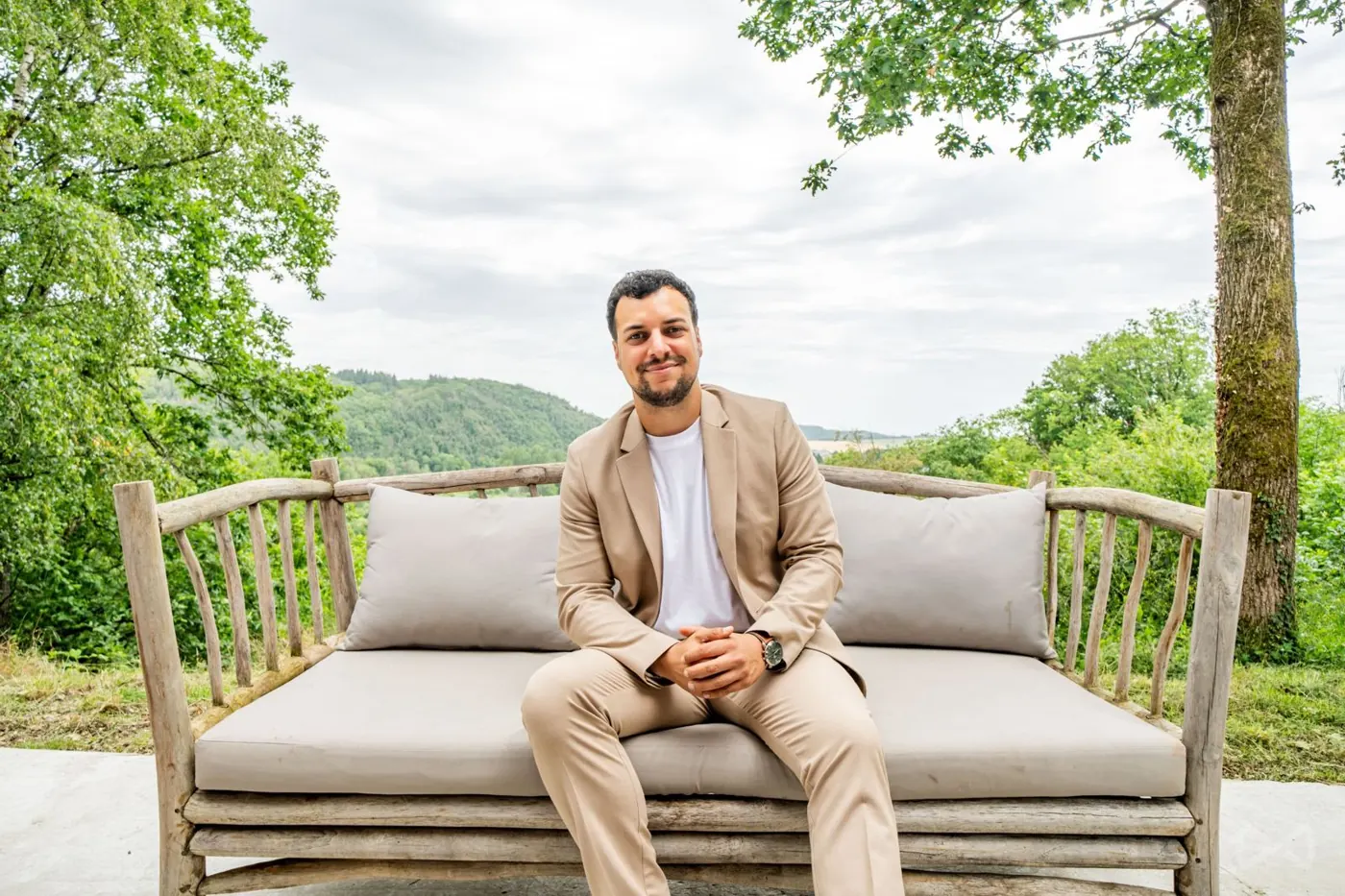 Geoffrey assis sur un banc en bois face à la nature